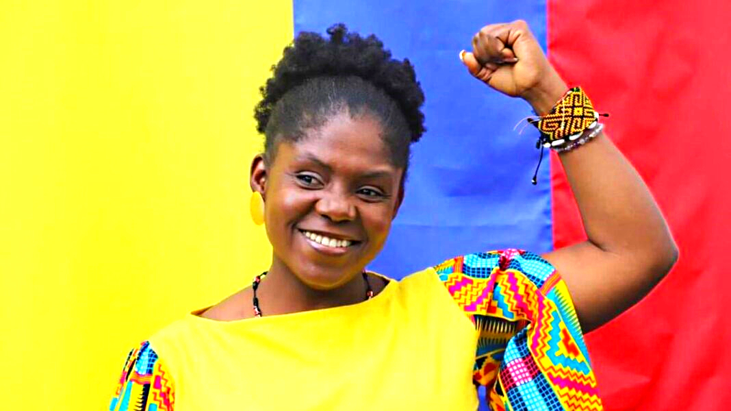 Francia Márquez vicepresidenta de Colombia en 2022 alzando un brazo con el puño cerrado, detrás la bandera de Colombia.